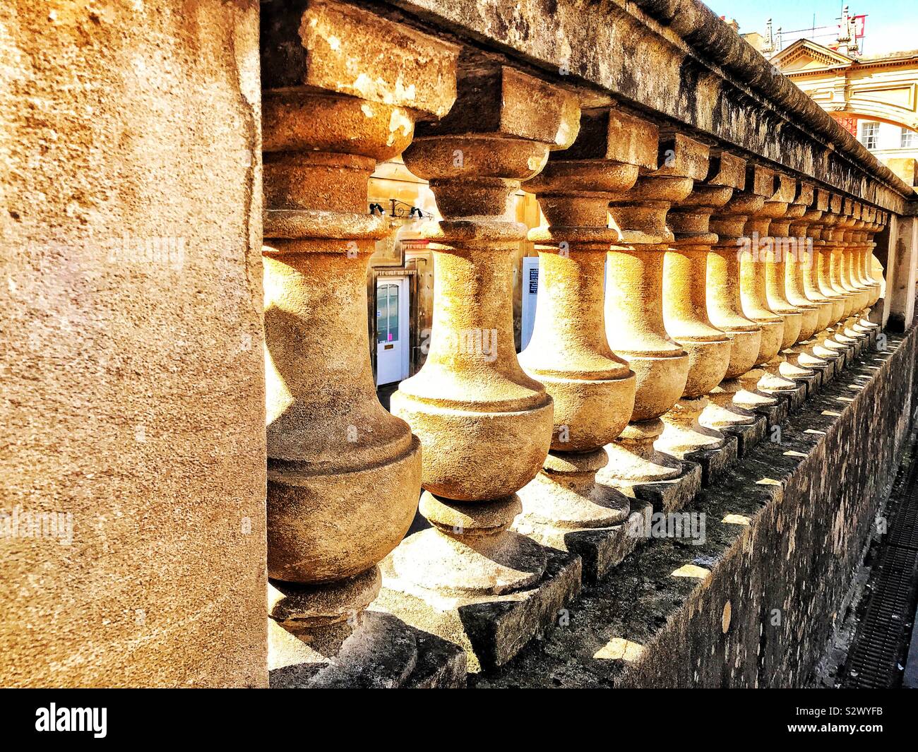 Detail einer reich verzierten, sonnenbeschienenen stein Wand auf dem Gelände der römischen Bäder in Bath, Somerset, England. Stockfoto