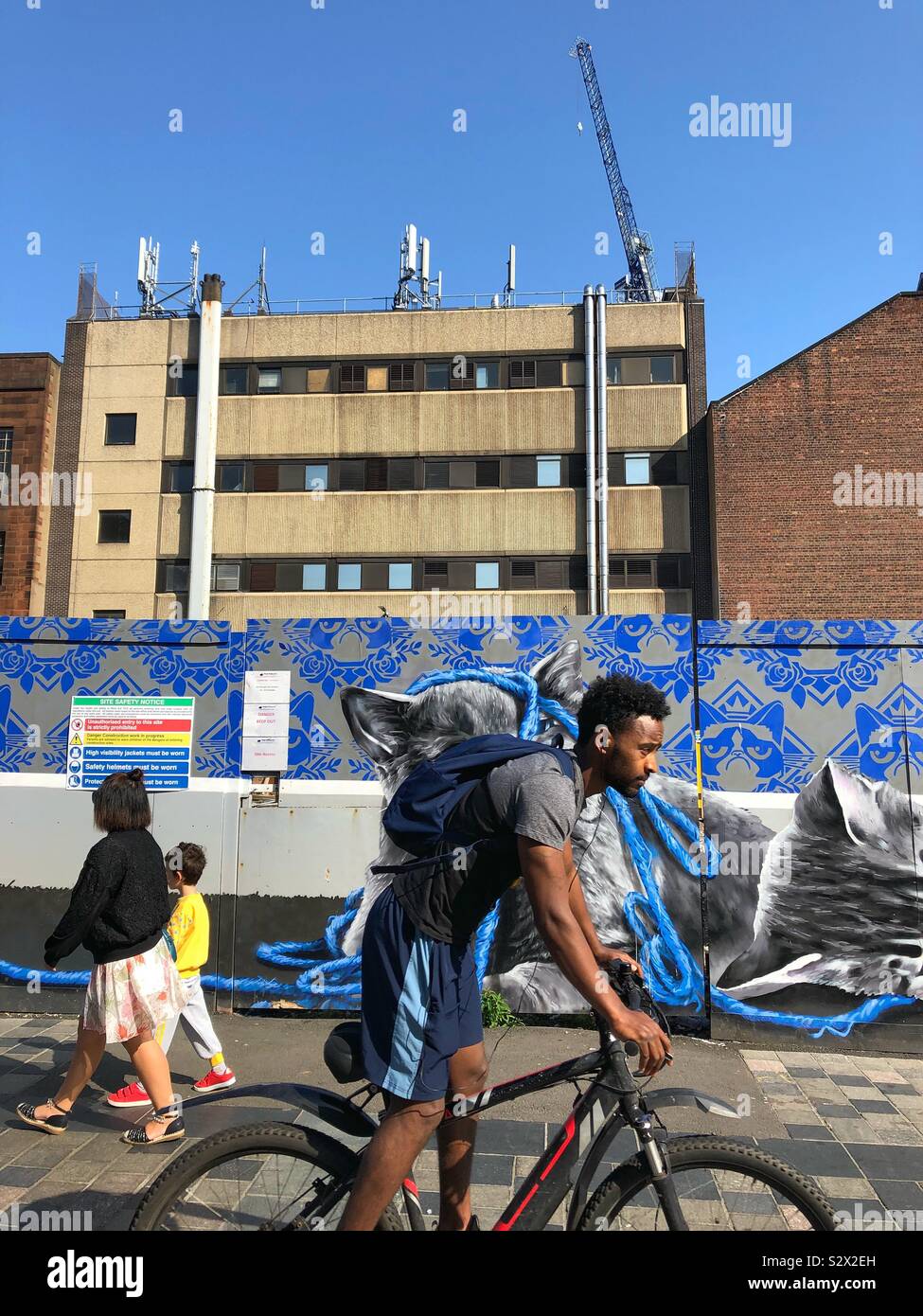 Man radelt die Sauchiehall Street im Stadtzentrum von Glasgow entlang, im Hintergrund laufen Bauarbeiten und Graffiti Street Art. - Smartphone-aufgenommenes Stockfoto