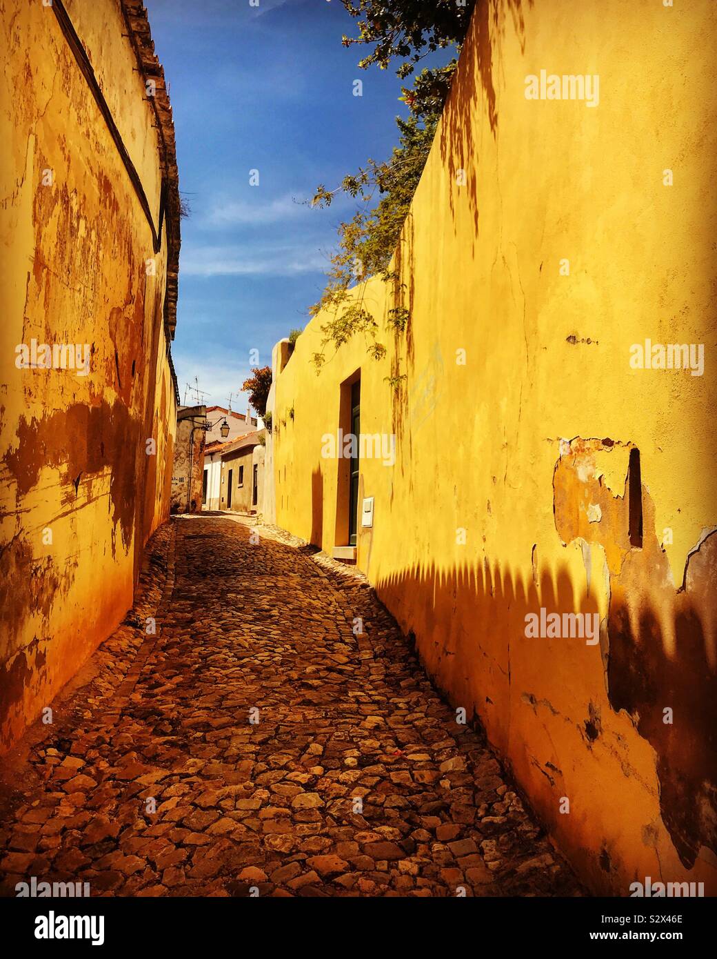 Schmale Straße zwischen gelben Wänden in Silves Stadt, Portugal Stockfoto