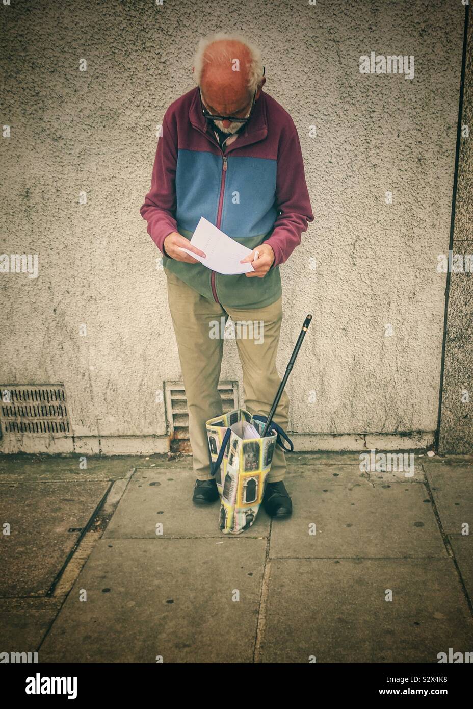 Glatzköpfige mann Studium Papier auf der Straße, Finchley, London. - Smartphone-aufgenommenes Stockfoto