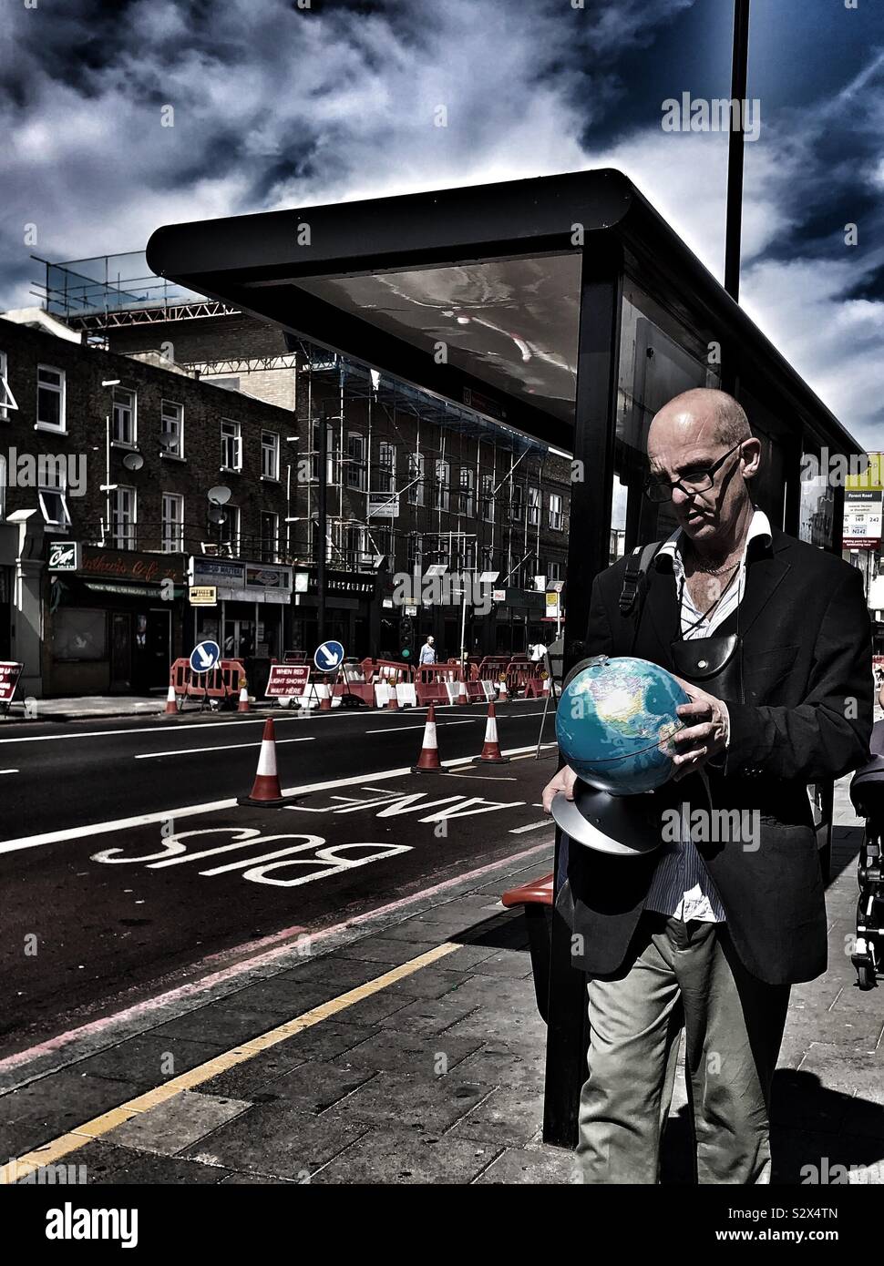 Mann hält eine Weltkugel in der Hand in London - Smartphone-aufgenommenes Stockfoto