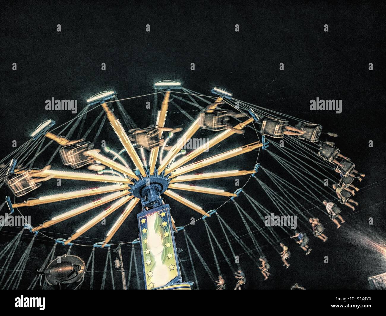 Menschen mit einem County Fair. Das Schwingen oder Stuhl Swing Ride ist ein Fahrgeschäft, dass ist eine Variation auf dem Karussell, bei dem die Sitze von der rotierenden oben auf dem Karussell ausgesetzt sind. Stockfoto