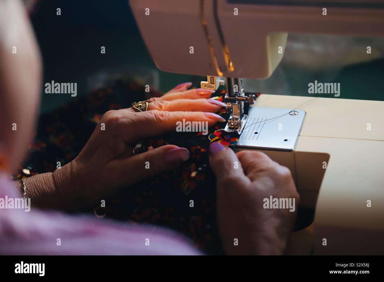 À Frau ein Kleid zu nähen. Nähmaschine. Freizeitaktivität. Stockfoto