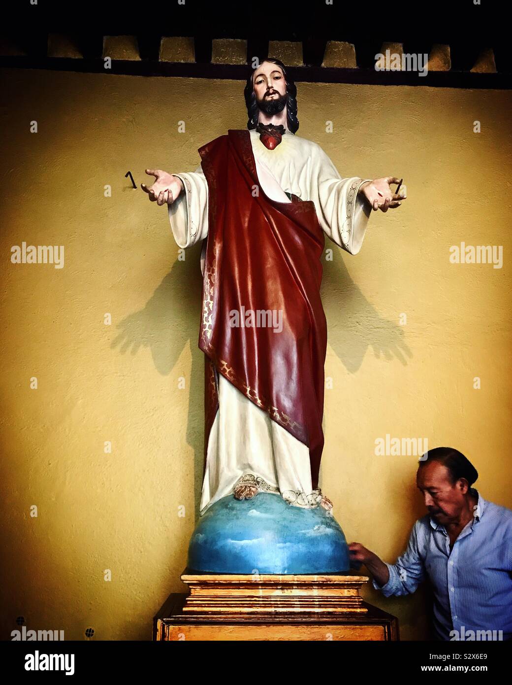 Ein Mann reinigt eine Skulptur der Heiligen Herzen von Jesus Christus in der Kirche in San Angel Nachbarschaft in Mexiko City, Mexiko Stockfoto