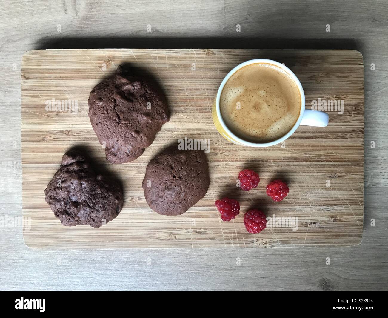 Hausgemachte Schokolade Bier cookies mit frischen Himbeeren und Kappe von Kaffee auf dem Holzbrett. - Smartphone-aufgenommenes Stockfoto