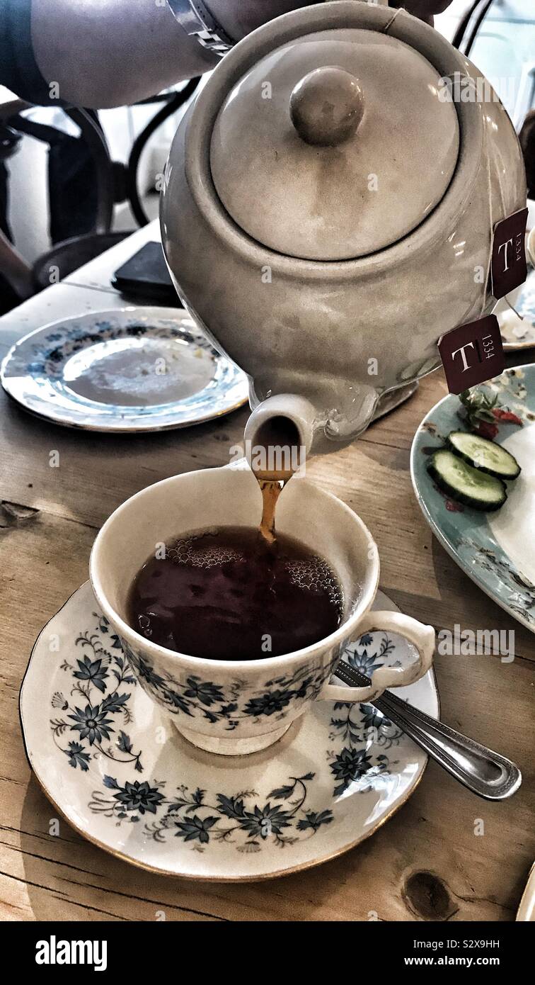 Man gießt eine Tasse Kaffee aus einer Teekanne in ein China Tasse mit Untertasse Stockfoto
