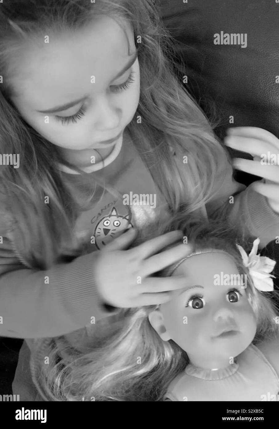 Kleine Mädchen spielen mit Puppen Haar, Schwarz und Weiß Stockfoto