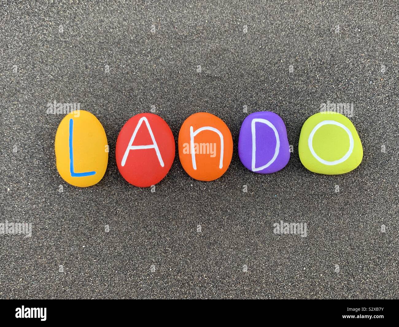 Lando, männliche italienische Vornamen besteht aus farbigen Steinen über schwarzen vulkanischen Sand Stockfoto
