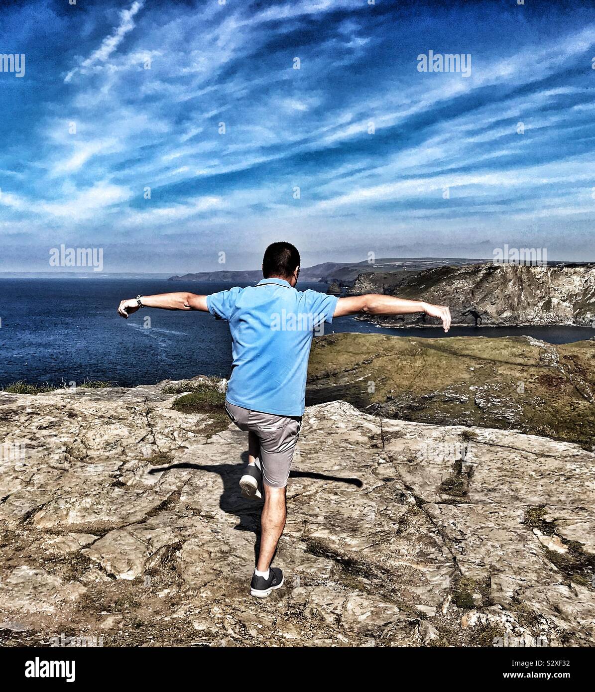Mann auf der Klippe übt sein Kung Fu bewegt sich Tintagel Castle mit Blick auf den Atlantik, Cornwall, Großbritannien - Smartphone-aufgenommenes Stockfoto
