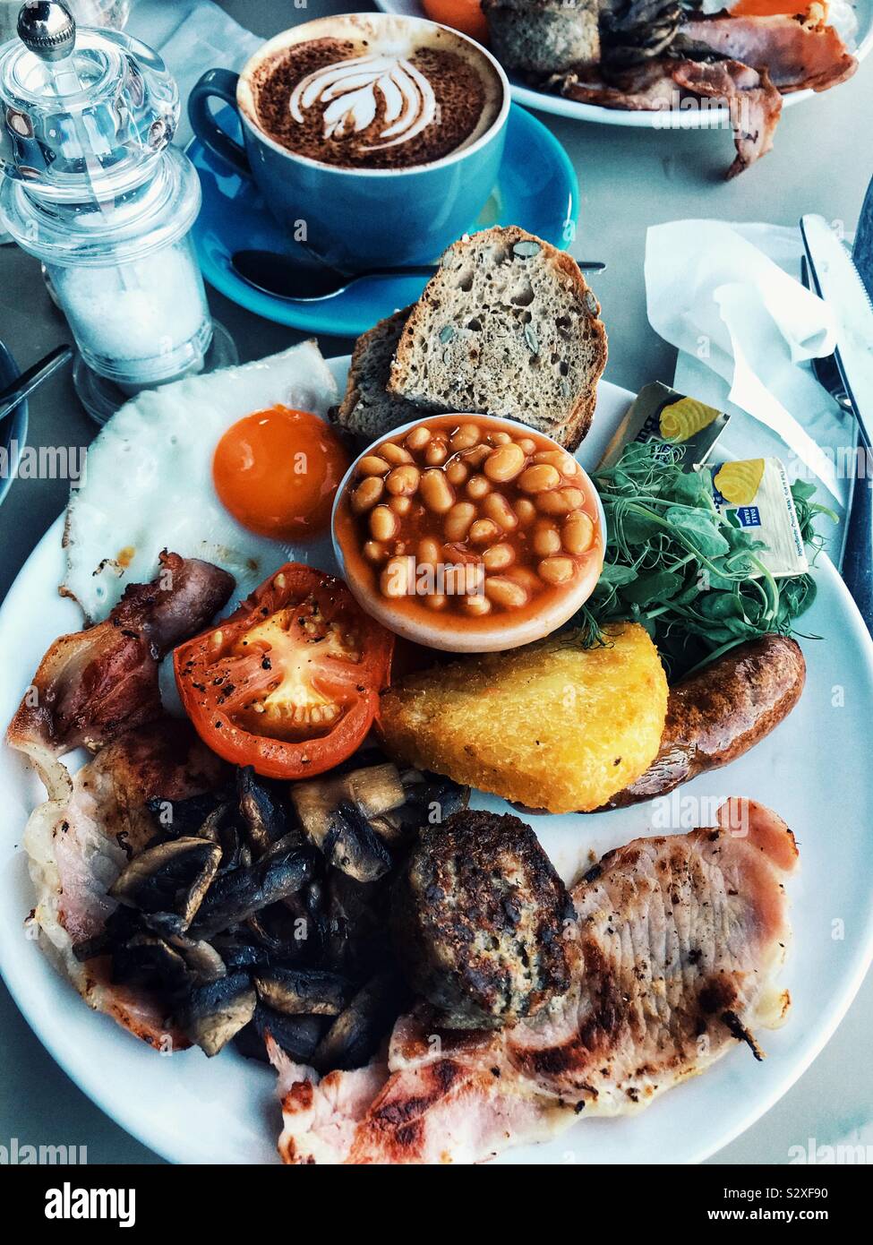 Englisches Frühstück Pfannengerichte und einem Cappuccino mit Herz Kunst Stockfoto