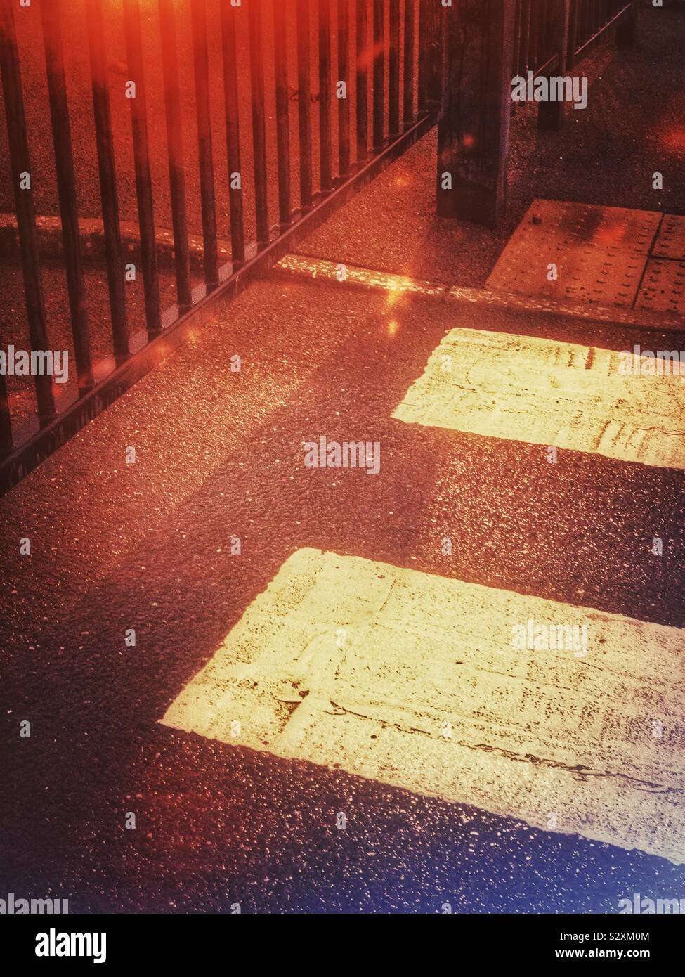 Fußgängerüberweg neben Metal Gate in der Nacht. Stockfoto