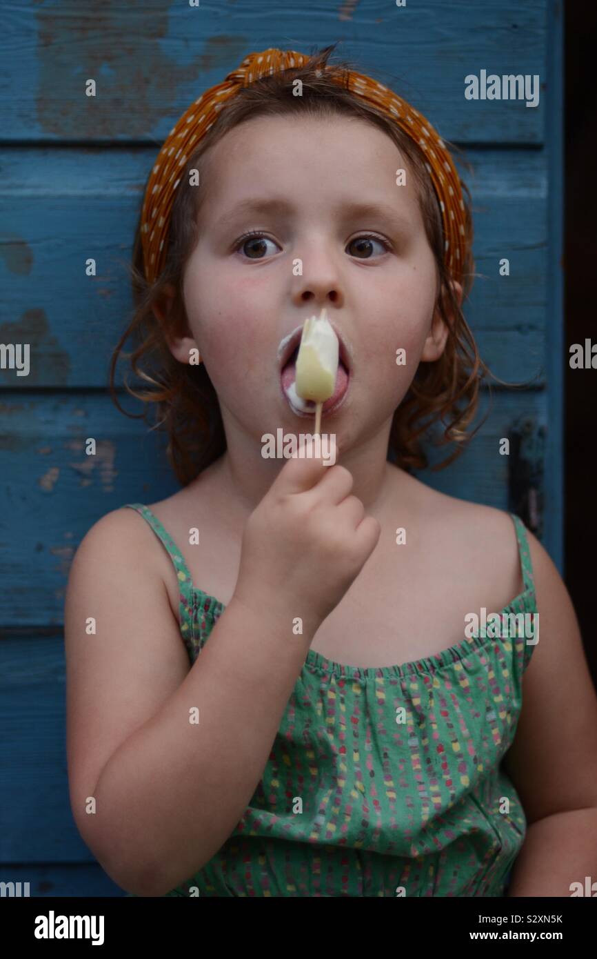 Kleines Mädchen Eis essen gegen den blauen Schuppen Hintergrund Stockfoto