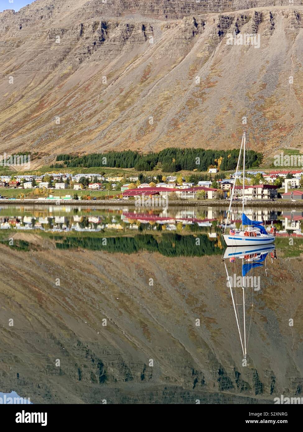 Isafjordur, Island - 26. September 2019: fantastisch hellen Reflexionen im Wasser auf einem warmen Herbst morgens Hafen. - Smartphone-aufgenommenes Stockfoto
