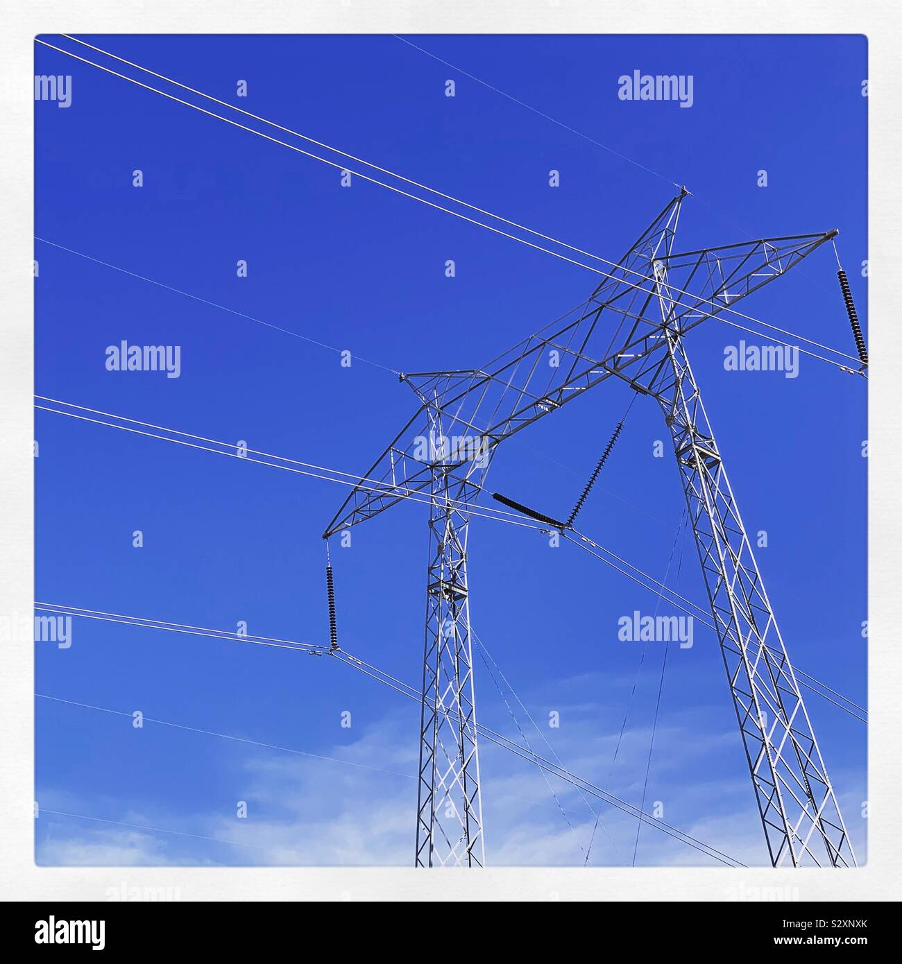 Sendemast und Drähte vor blauem Himmel Stockfoto