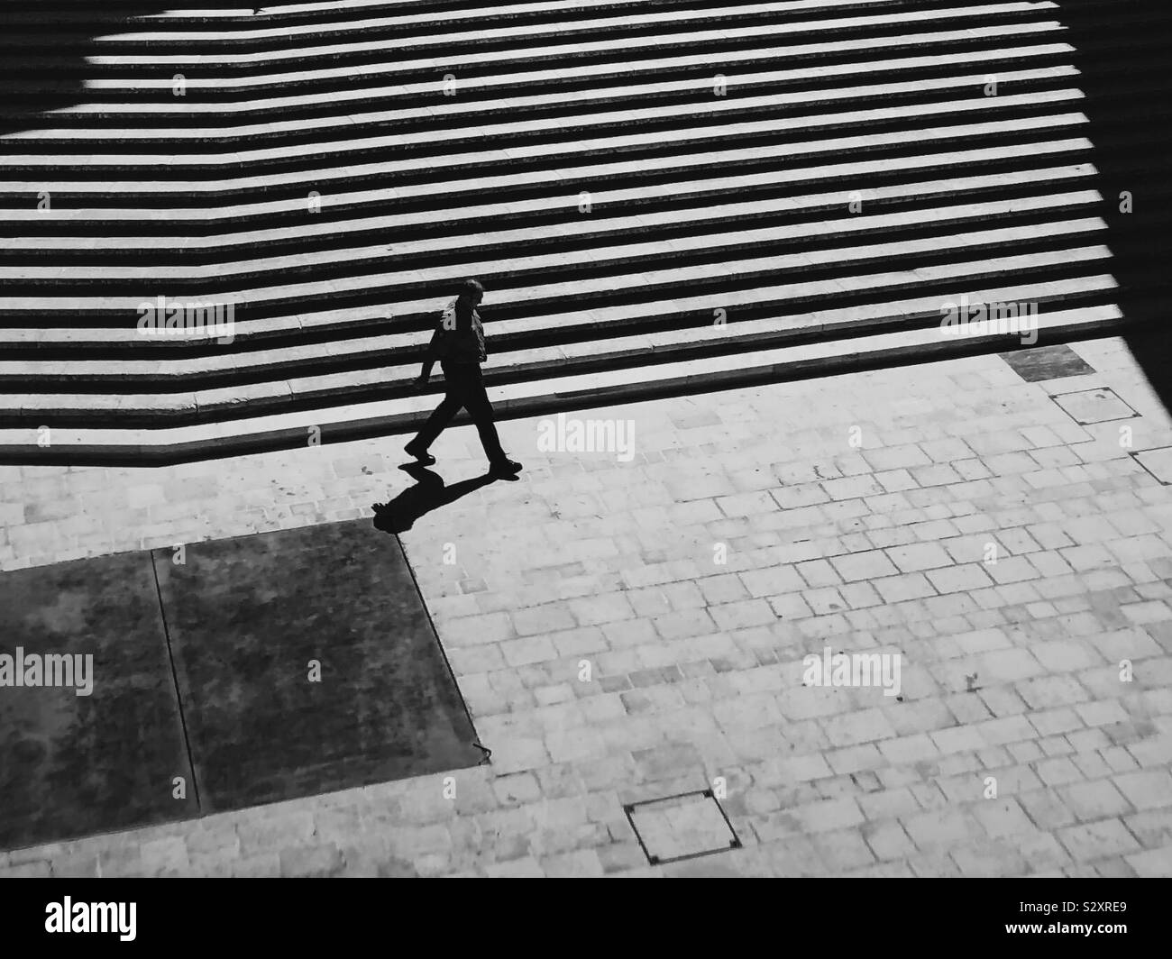 Einsame monochrome Fußgänger gegen Schritte. Stockfoto