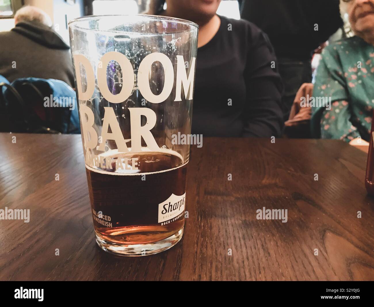 Ein halbes Pint getrunken von Doom Bar Amber ale auf einen Tisch. Stockfoto