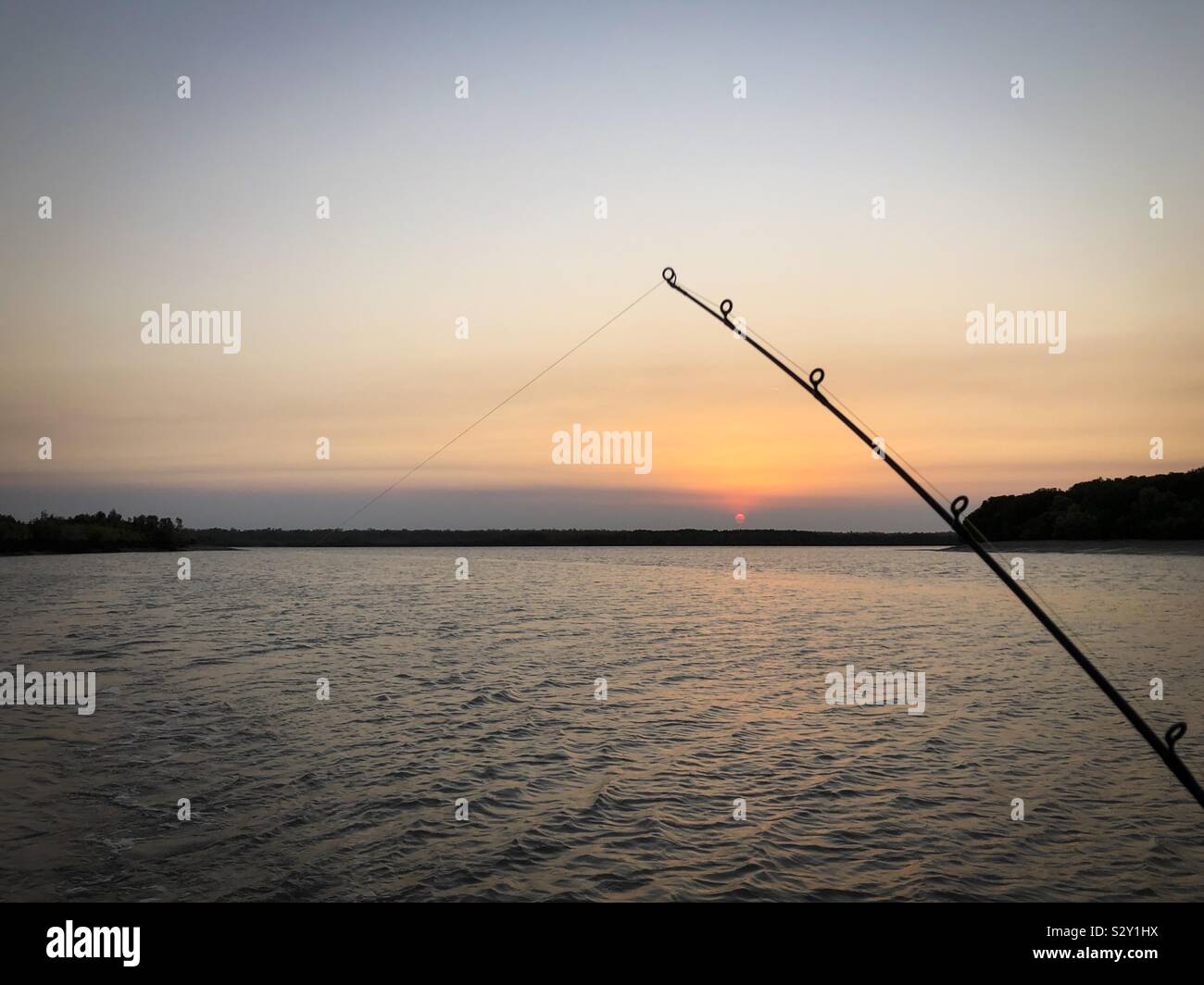Angelrute und Sonnenuntergang über den Adelaide River im Northern Territory von Australien. Stockfoto
