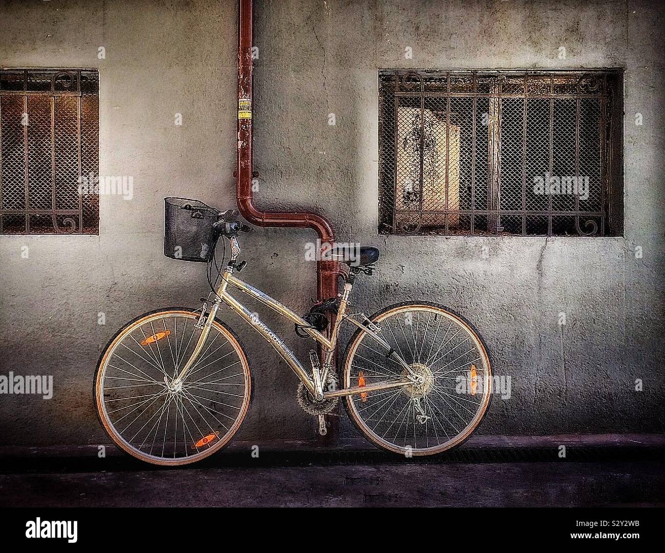 Fahrrad lehnte sich gegen eine Wand unter einem Fenster Stockfoto