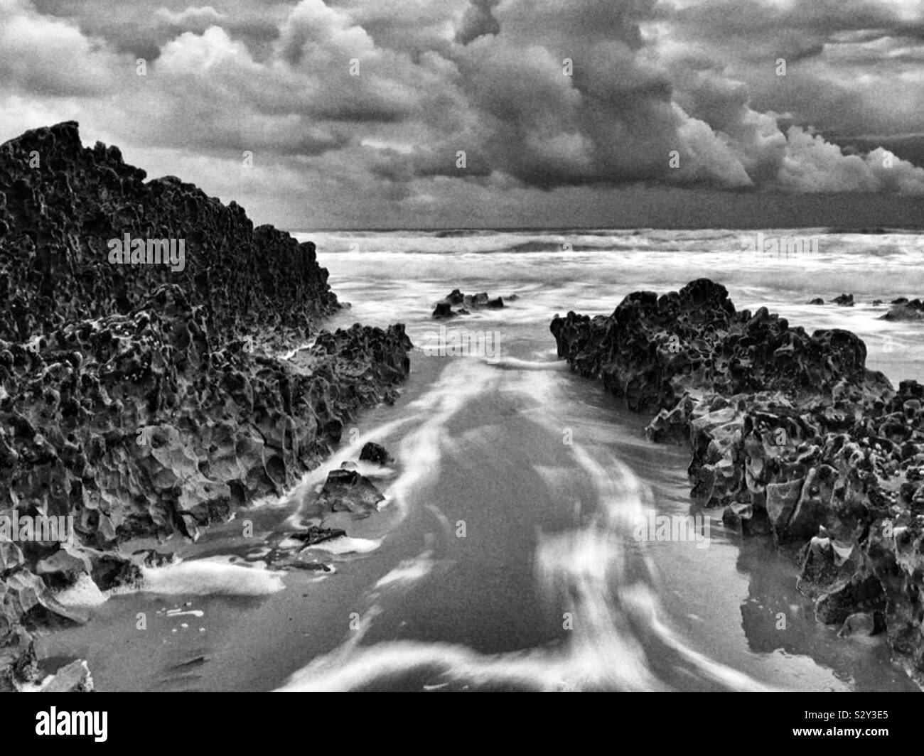 Wasser, das sich durch Felsen auf ein Waliser Surf Beach Stockfoto