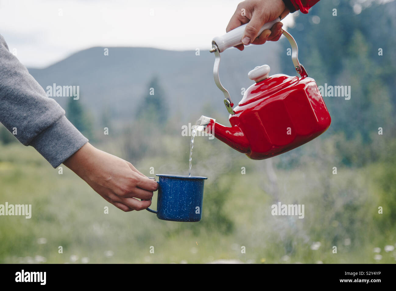 Gießt Wasser in eine Tasse beim Camping Stockfoto