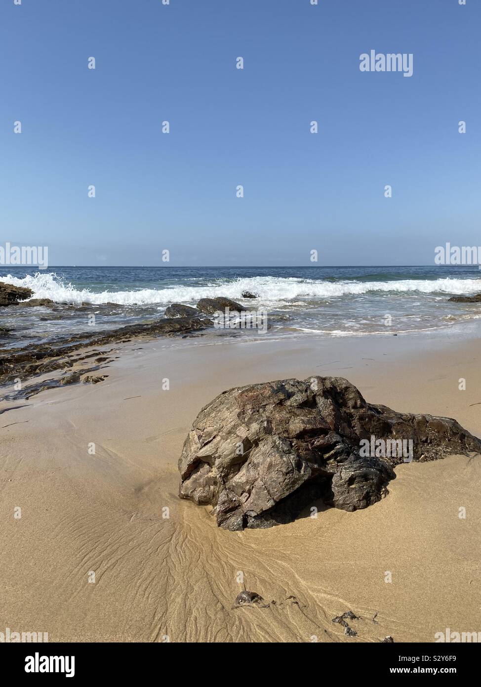 Große Felsformationen auf dem Sand mit Blick auf den Pazifischen Ozean auf der Kalifornischen Strand - Smartphone-aufgenommenes Stockfoto