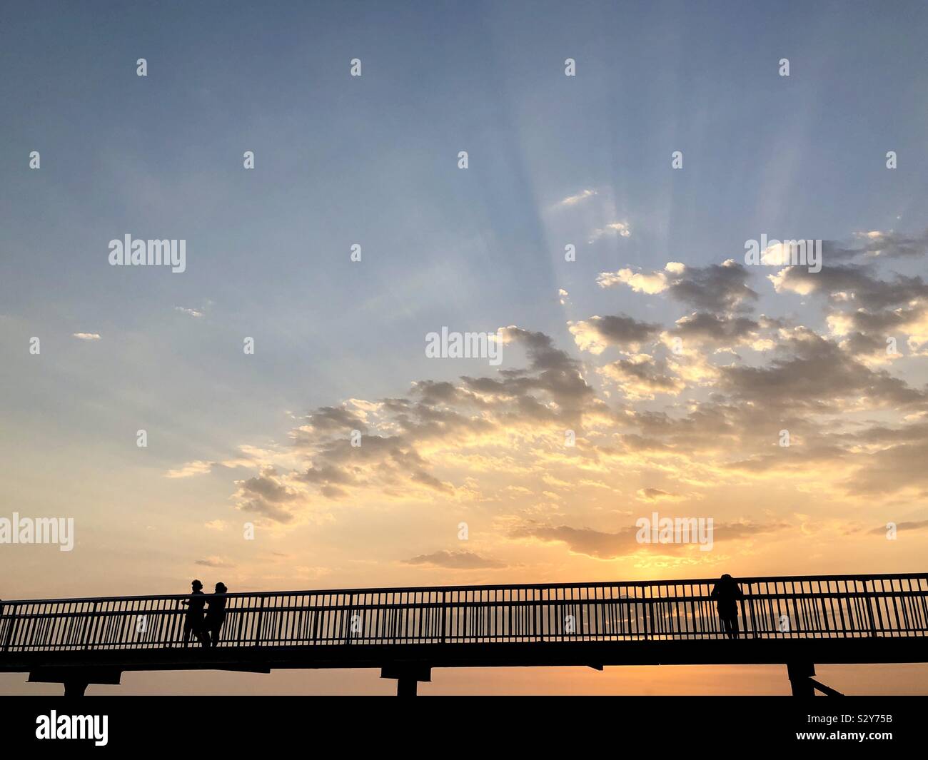 Silhouette von Menschen auf eine Fußgängerbrücke bei Sonnenuntergang. Stockfoto