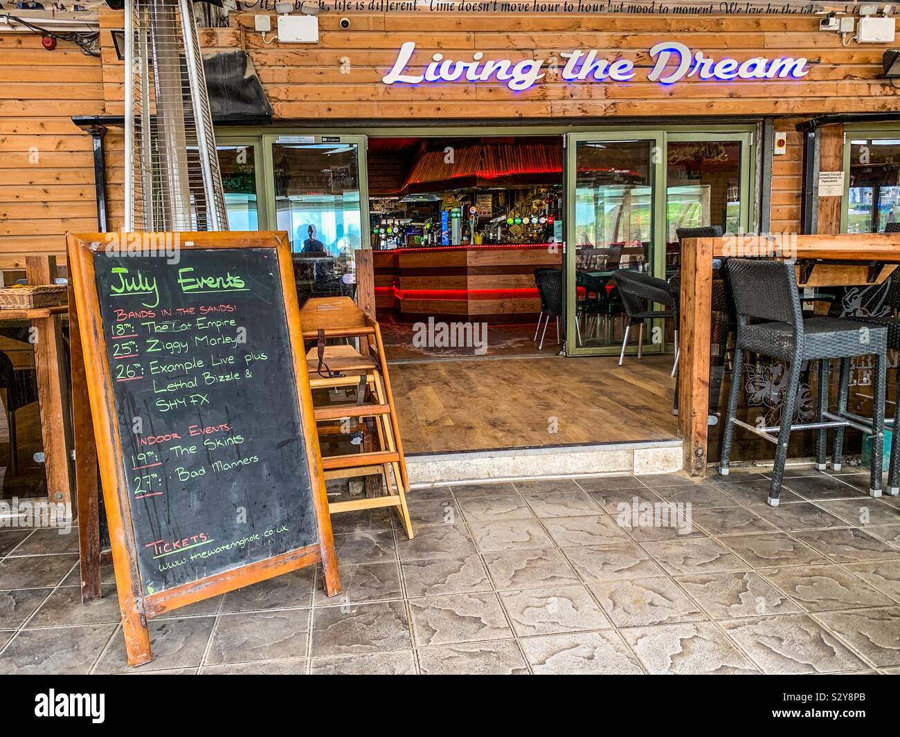 Living the Dream Zeichen außerhalb des Watering Hole Bar in Perranporth in Cornwall. Stockfoto