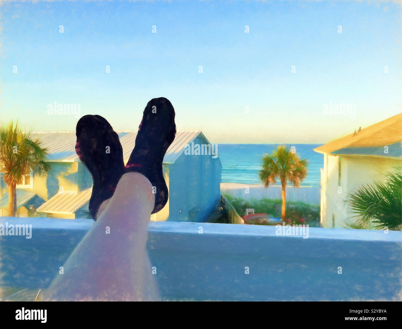 Eine malerische Aussicht auf das Meer von einer zweiten Sitzreihe Eigentumswohnungen Balkon. Eine Frau hat ihre Füße aufgestützt auf der Veranda Geländer. Dieses Bild hat eine malerische strukturierte Wirkung. Stockfoto