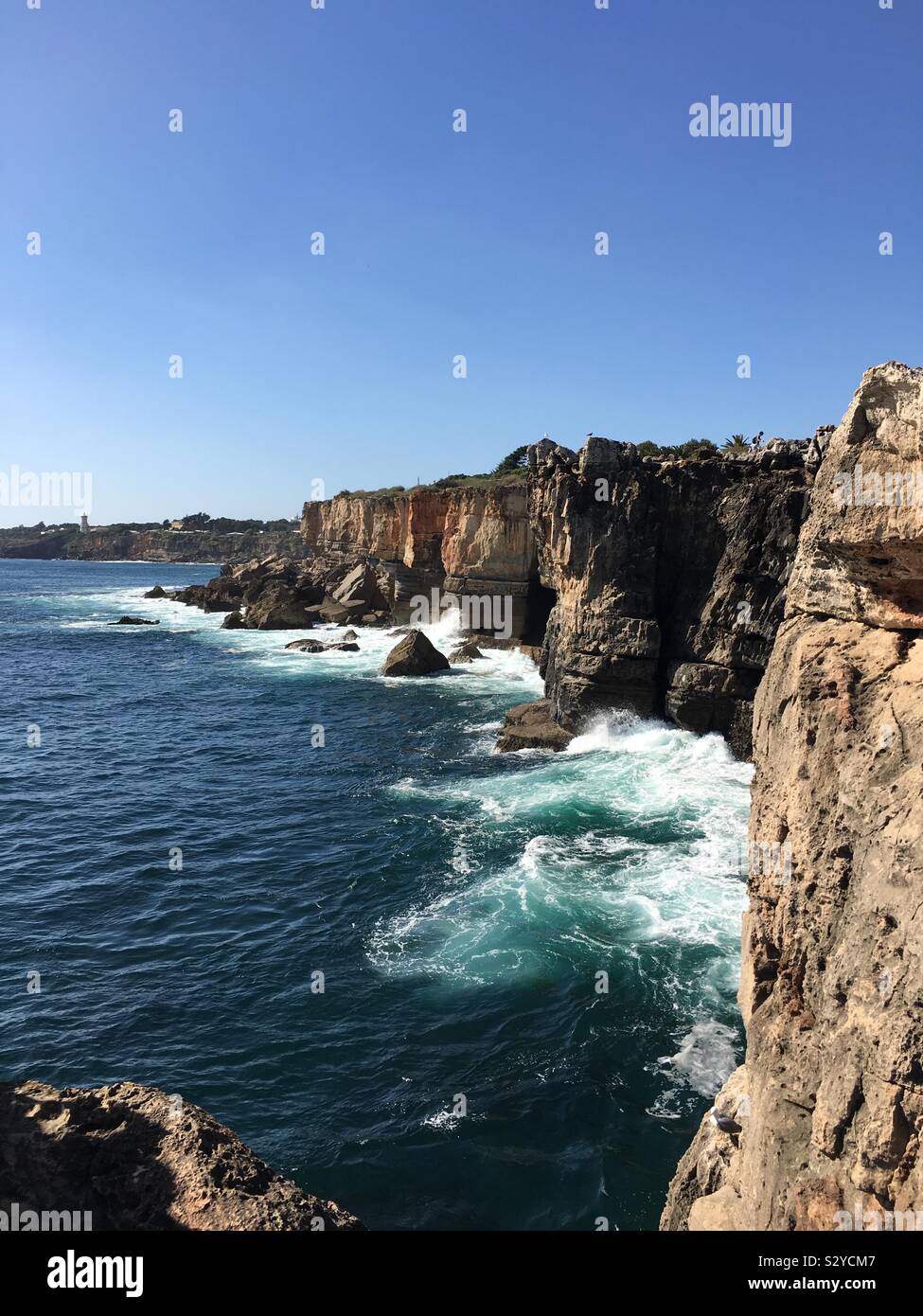 Bei der Stadt Cascais spüren Sie den frischen Wind in Richtung zu ihnen kommen und zu den Klängen des Meeres berühren die Felsen hören Stockfoto