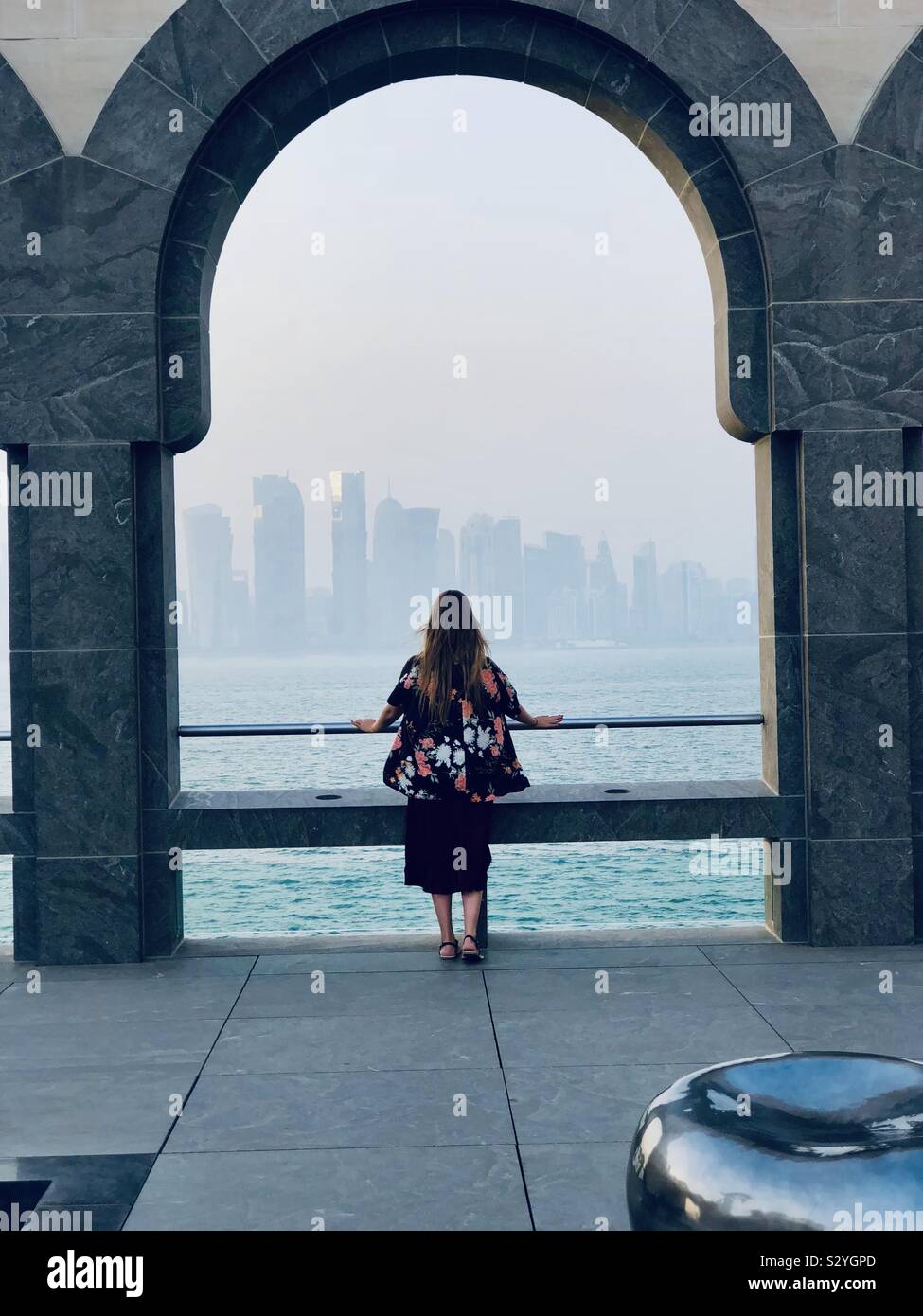 Mädchen im Kimono mit Blick auf die Skyline von Doha unter einem Bogen Stockfoto