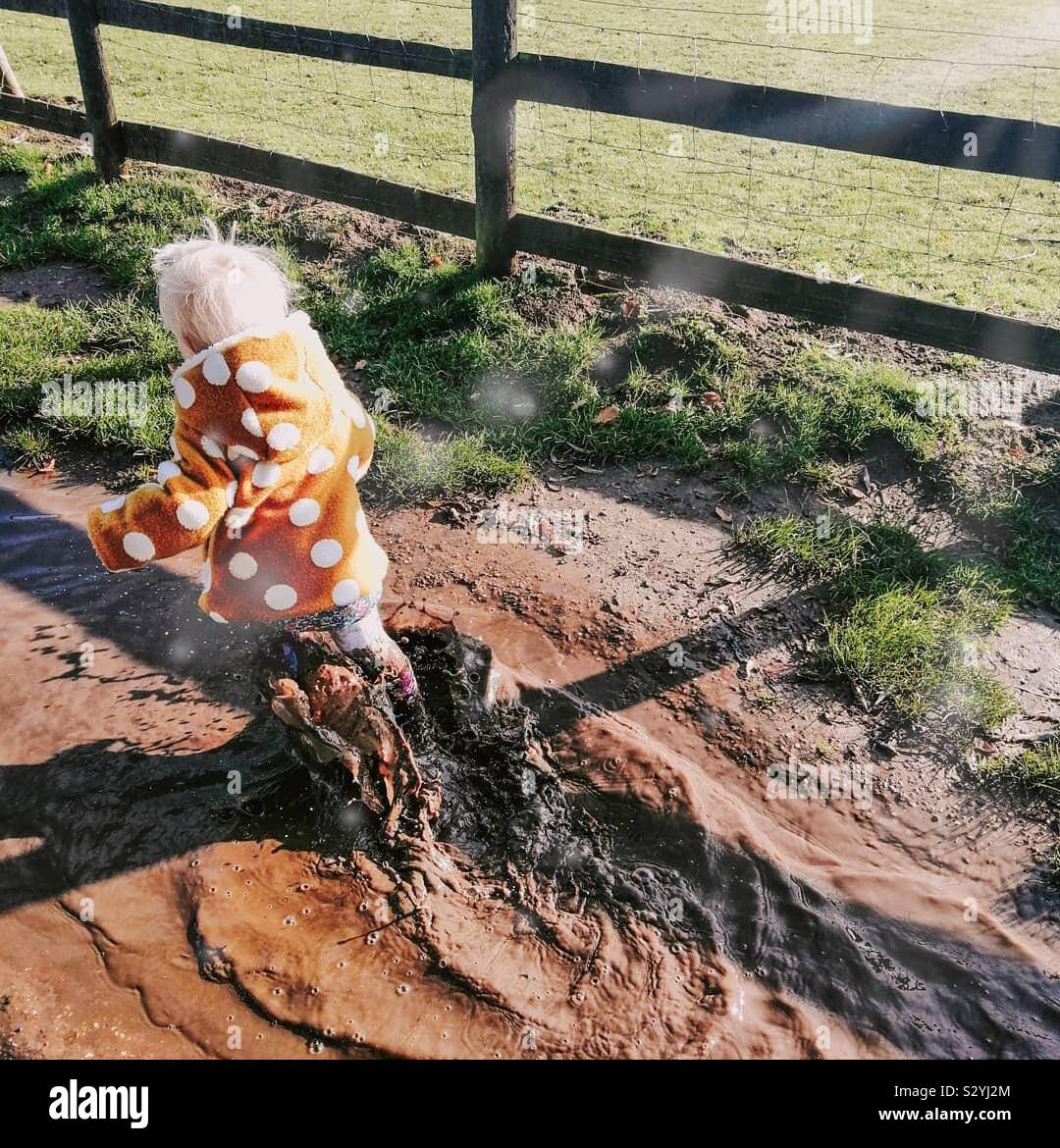 Kleinkind durch schlammige Pfützen Stockfoto