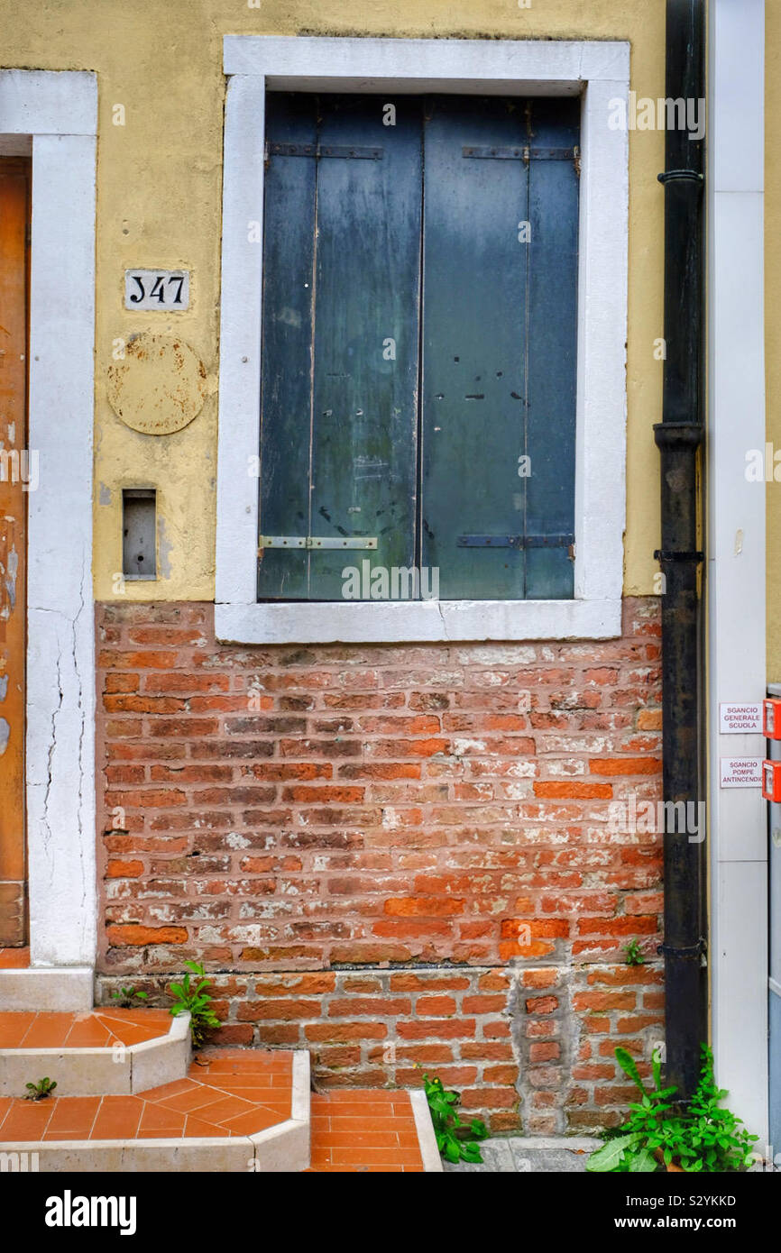 Bunte Wand mit einem Fenster, Fallrohr, Tür Haustür und Anlage - Smartphone-aufgenommenes Stockfoto