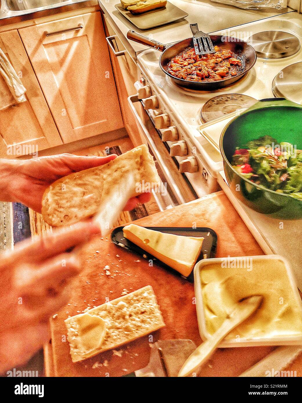 Mann Vorbereitung Mahlzeit in der schwedischen Küche. Braten Huhn, Salat zustimmen Baguette Stockfoto
