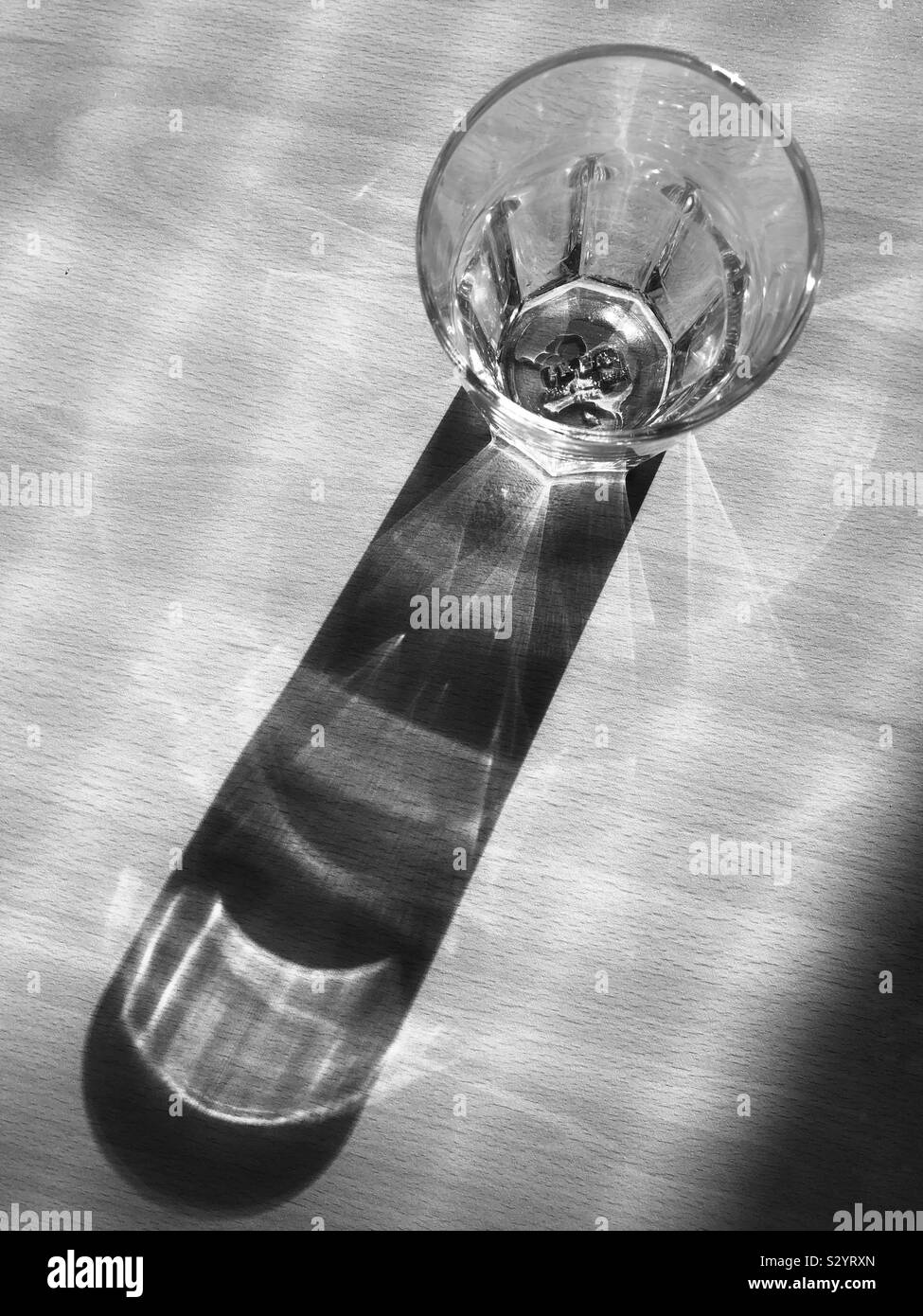 Ein Glas Wasser auf einen Tisch mit Schatten. Stockfoto