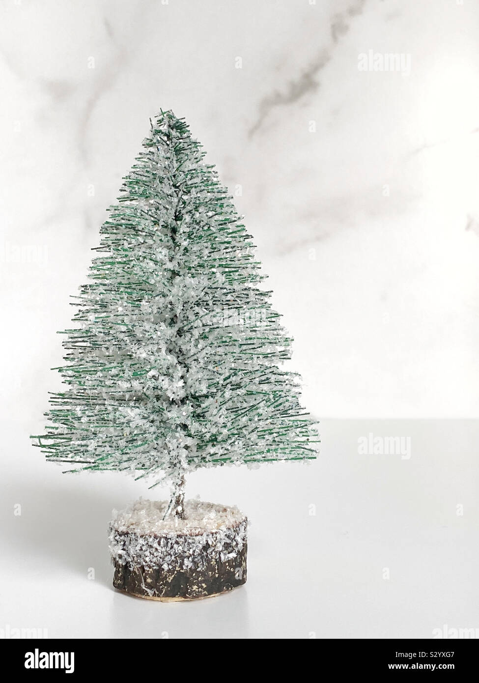 Mini Weihnachtsbaum mit Kunstschnee auf der Tischplatte weißer Hintergrund Stockfoto