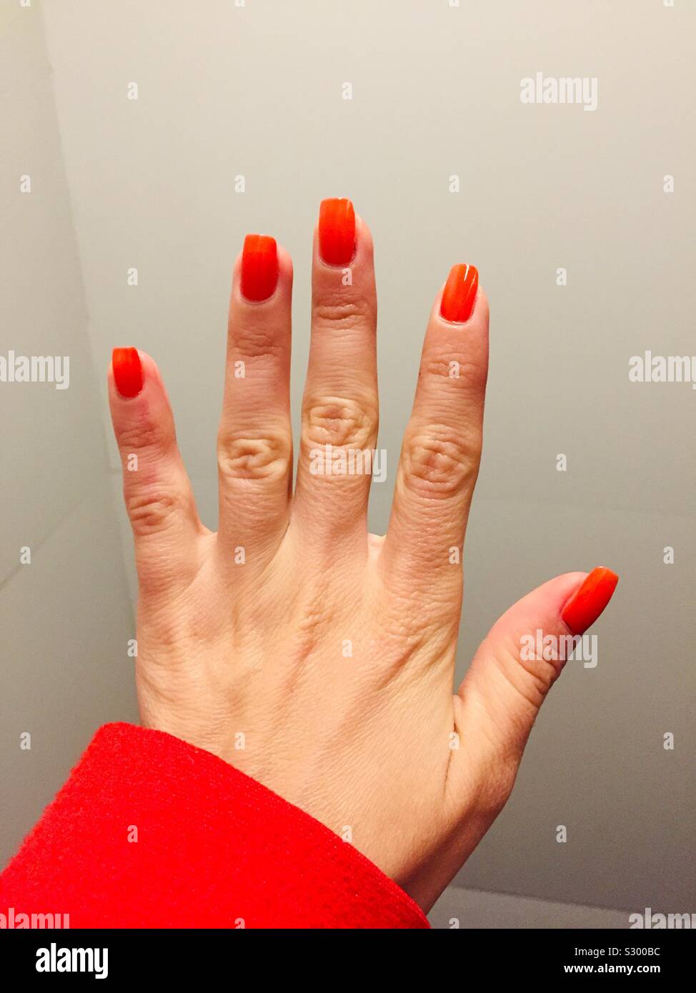 Rote nägel. Die jungen Mädchen Hand, deren Nägel haben rote Nagellack auf.  Roten Mantel mit dem roten Maniküre zu gehen Stockfotografie - Alamy