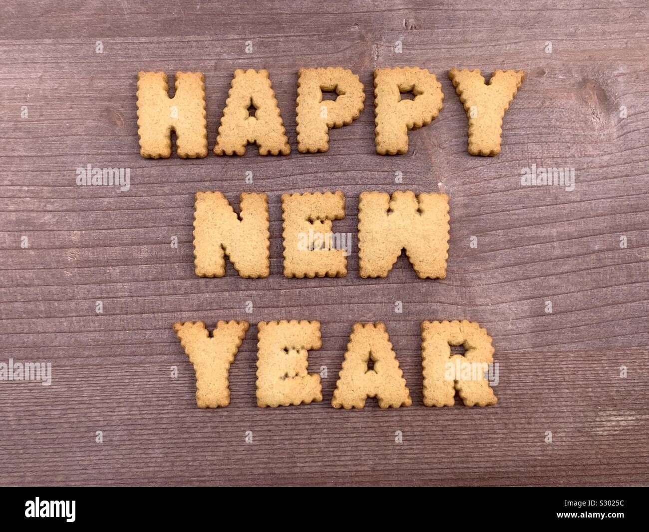 Frohes Neues Jahr komponiert mit Keks Buchstaben auf einem Holzbrett Stockfoto