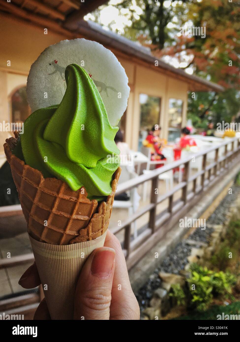 Matcha Grüntee Eis in eine Hand mit zwei Mädchen in traditionellen Kimonos Kleider auf der Terrasse zu sitzen. Fushimi Inari Taisha, Kyoto, Japan. Stockfoto