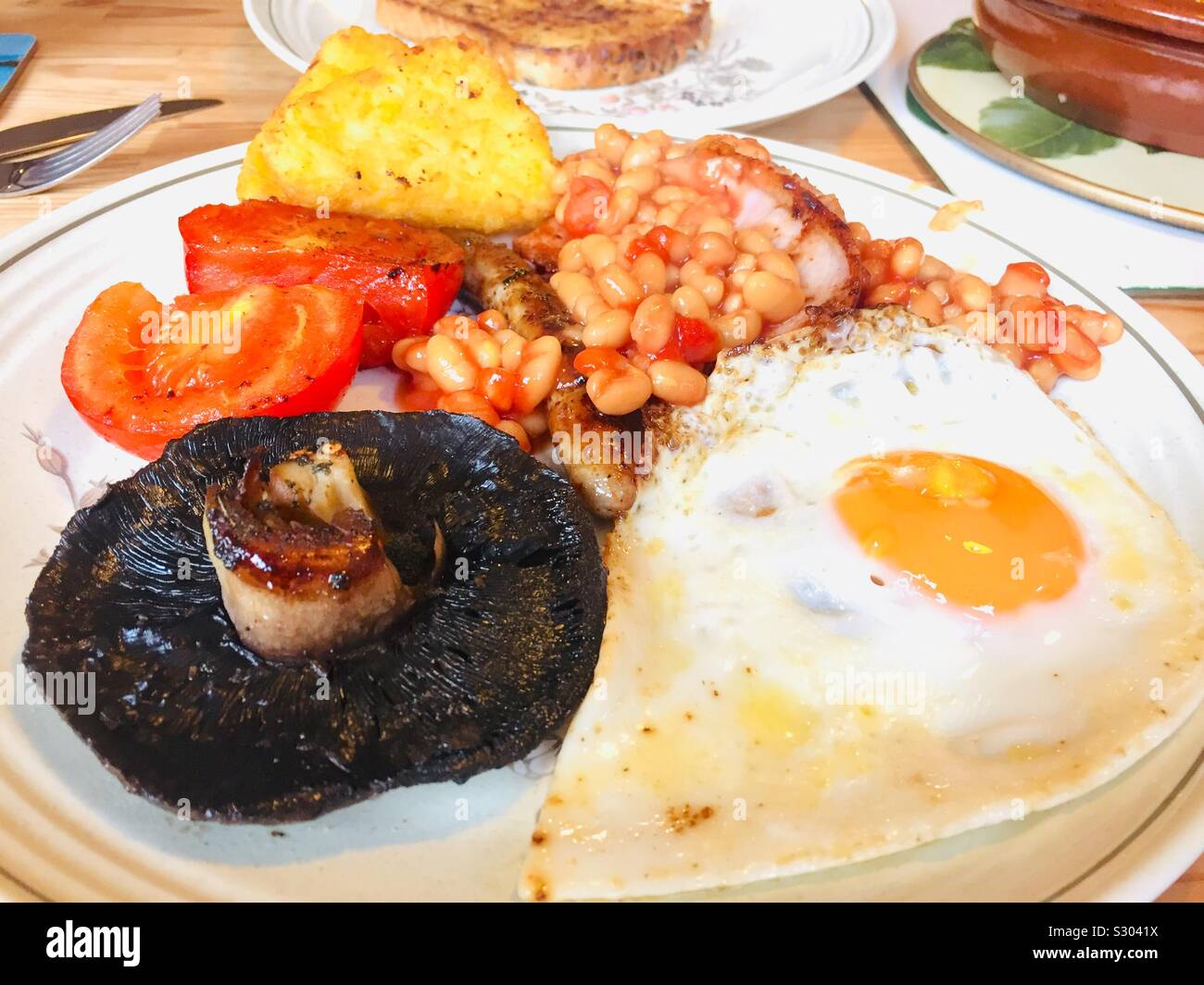Englisches Frühstück. Traditionelles warmes Frühstück gebackene Bohnen, Speck, Würstchen, Pilze, Spiegelei, Hash Browns und Tomaten. Stockfoto