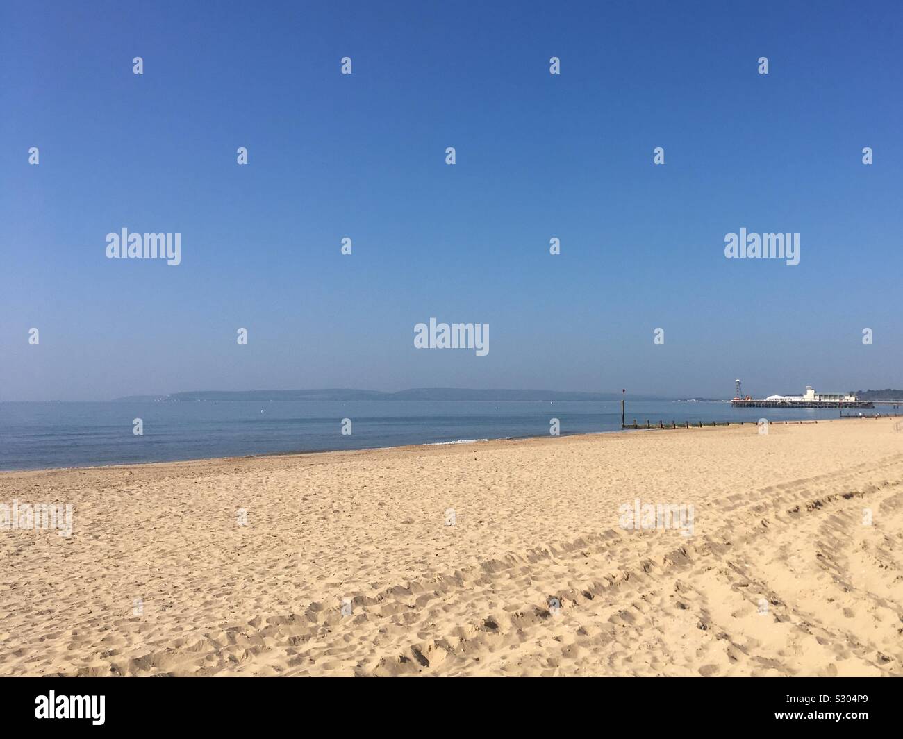 Bournemouth Strand mit der Seebrücke in der Ferne, an einem heißen, sonnigen Sommermorgen. Stockfoto