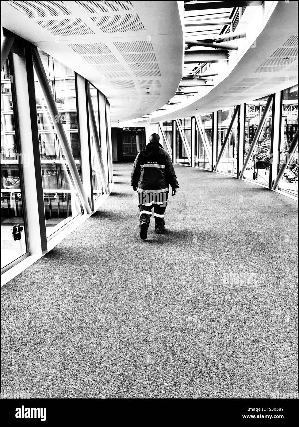 Mann Kreuzung Sky Bridge im Cape Town International Convention Centre, Südafrika. Schwarz-weiß Foto. - Smartphone-aufgenommenes Stockfoto