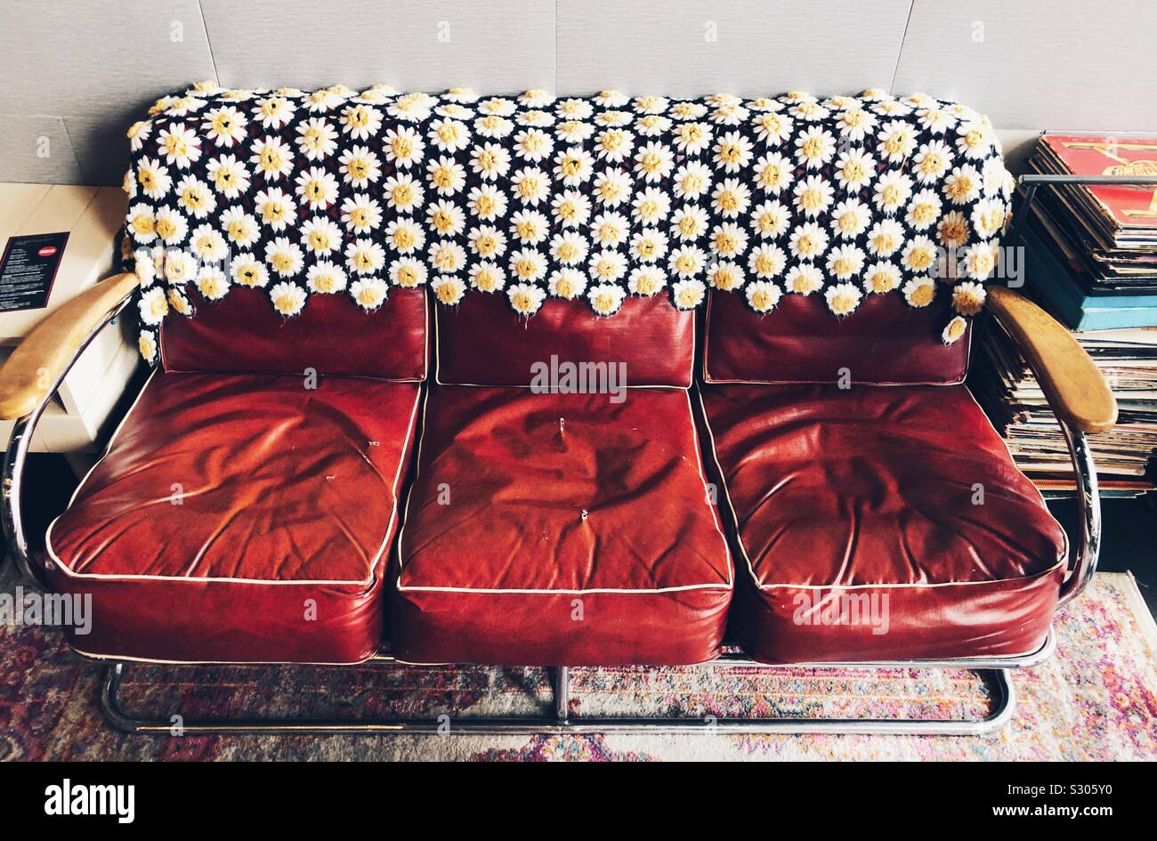 Vintage leder Sofa mit gestricken Gänseblümchen Abdeckung - Smartphone-aufgenommenes Stockfoto