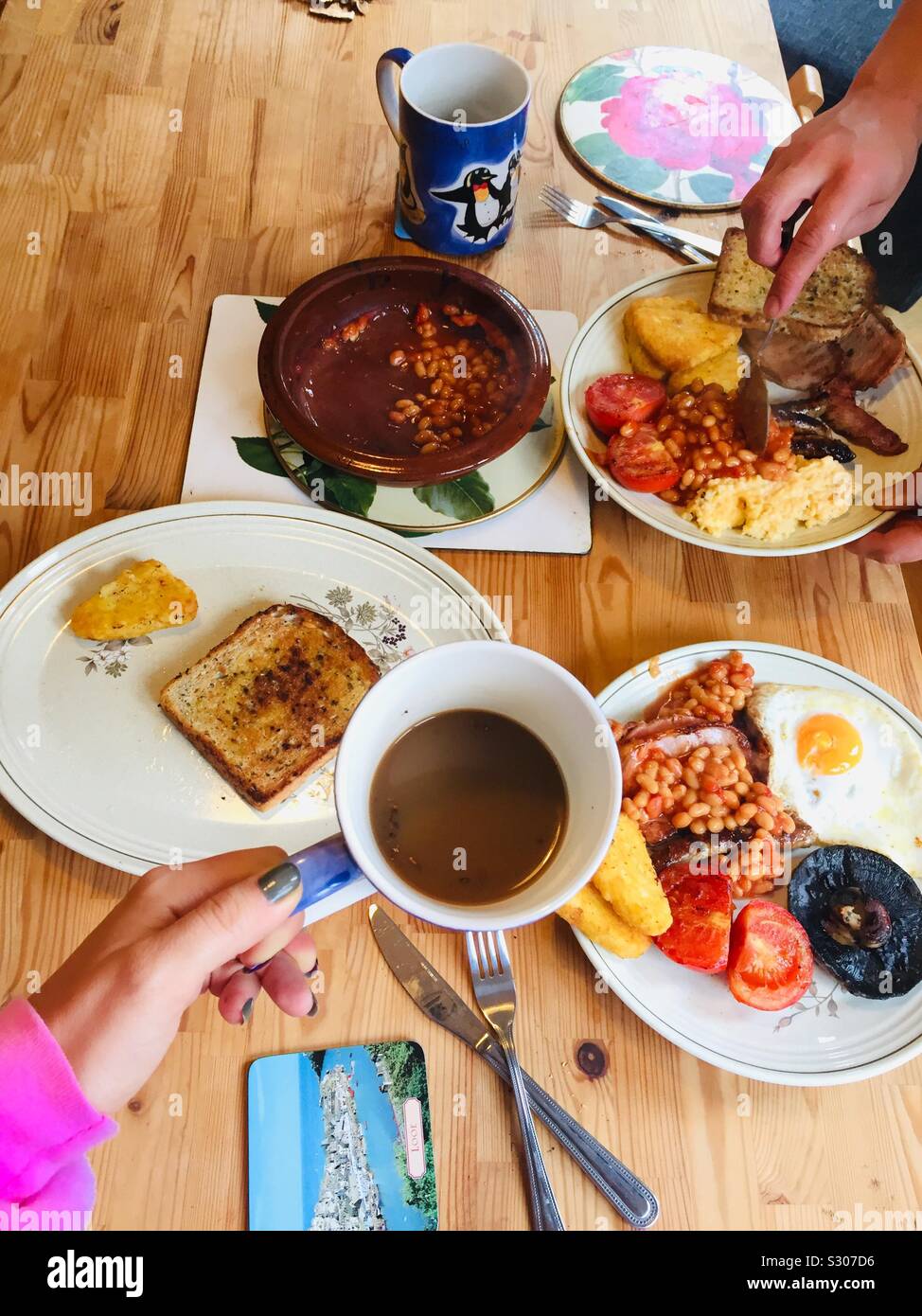 Englisches Frühstück auf dem Küchentisch. Gebraten in Olivenöl Brot, Pilze, Hash Browns, Bohnen, Eier, Tomaten, Wurst, Rührei, Kaffee und Tee. Hausgemachte warmes Frühstück für zwei. London Stockfoto