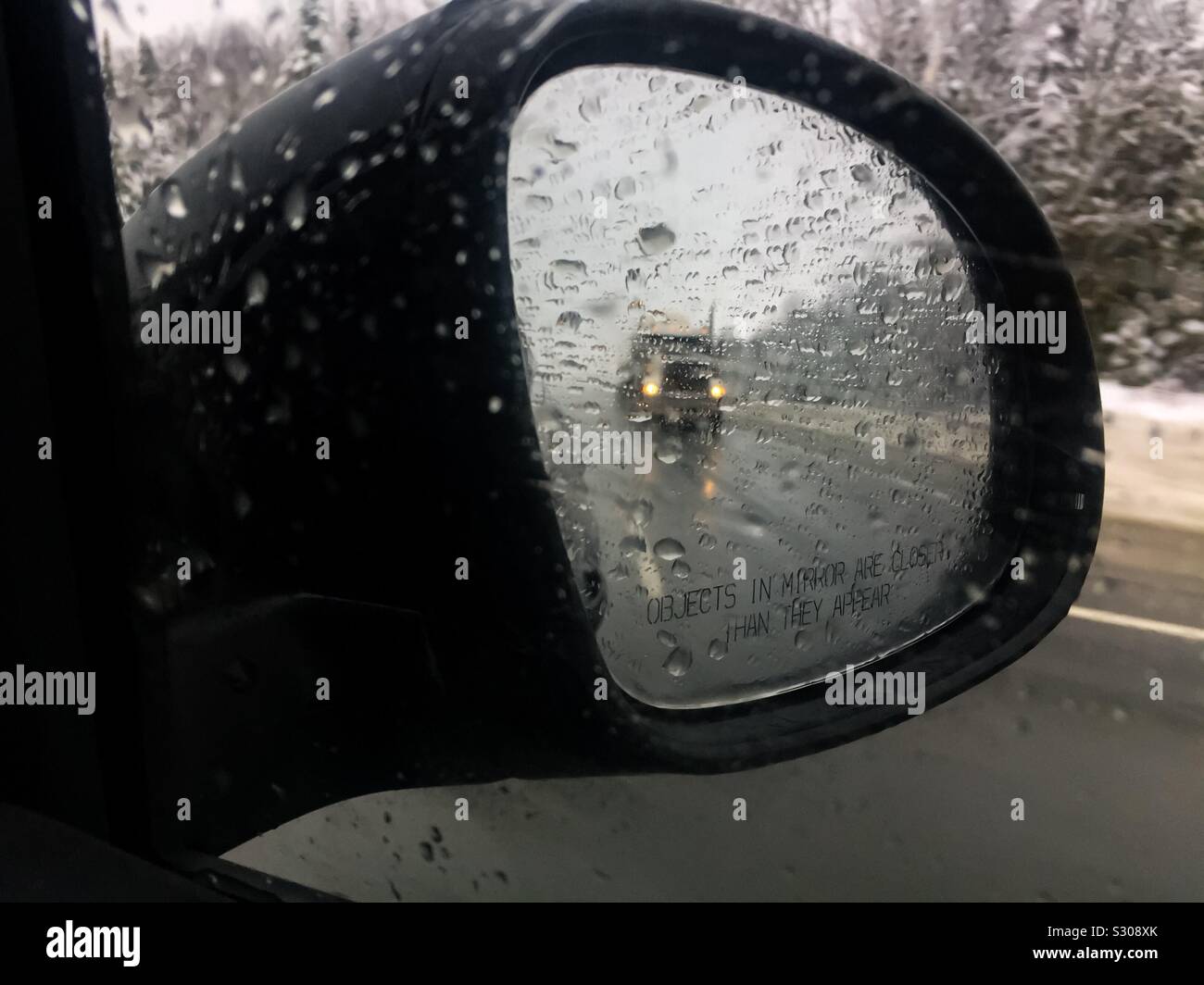 Truck auf der Autobahn bei strömendem Regen. Ansicht von der Beifahrerseite. Außenspiegel. Regnende Autos und Hunde. Kopierbereich - Smartphone-aufgenommenes Stockfoto