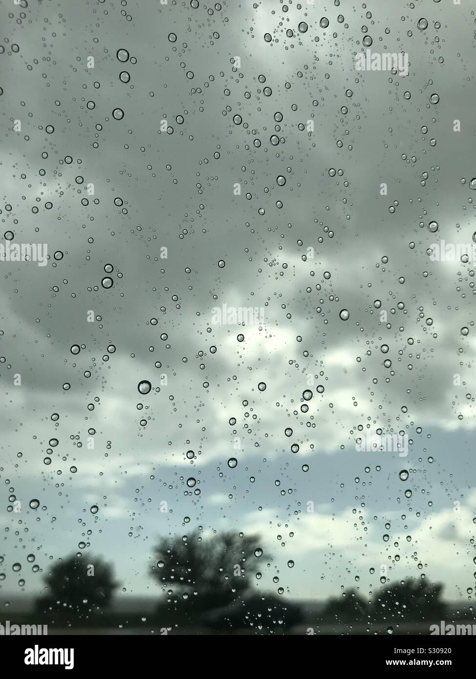 Regen fällt durch ein Fenster an einem bewölkten Tag Stockfoto