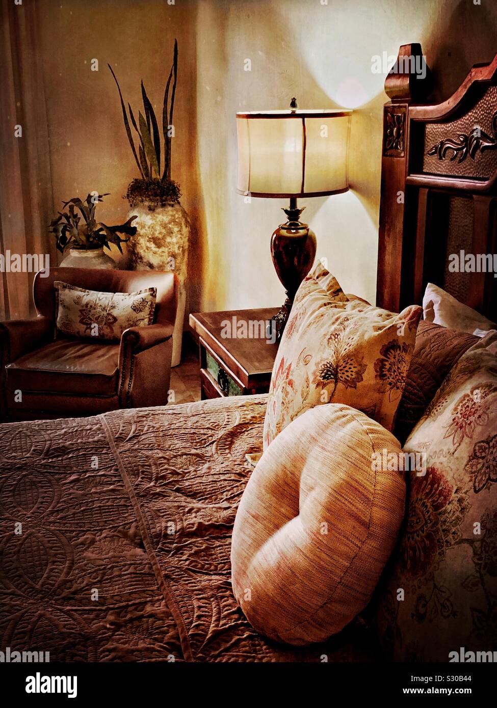 Teilweise mit Blick auf die Bett, Nachttisch, und Stuhl in einem gemütlichen Schlafzimmer in Jalisco. Stockfoto