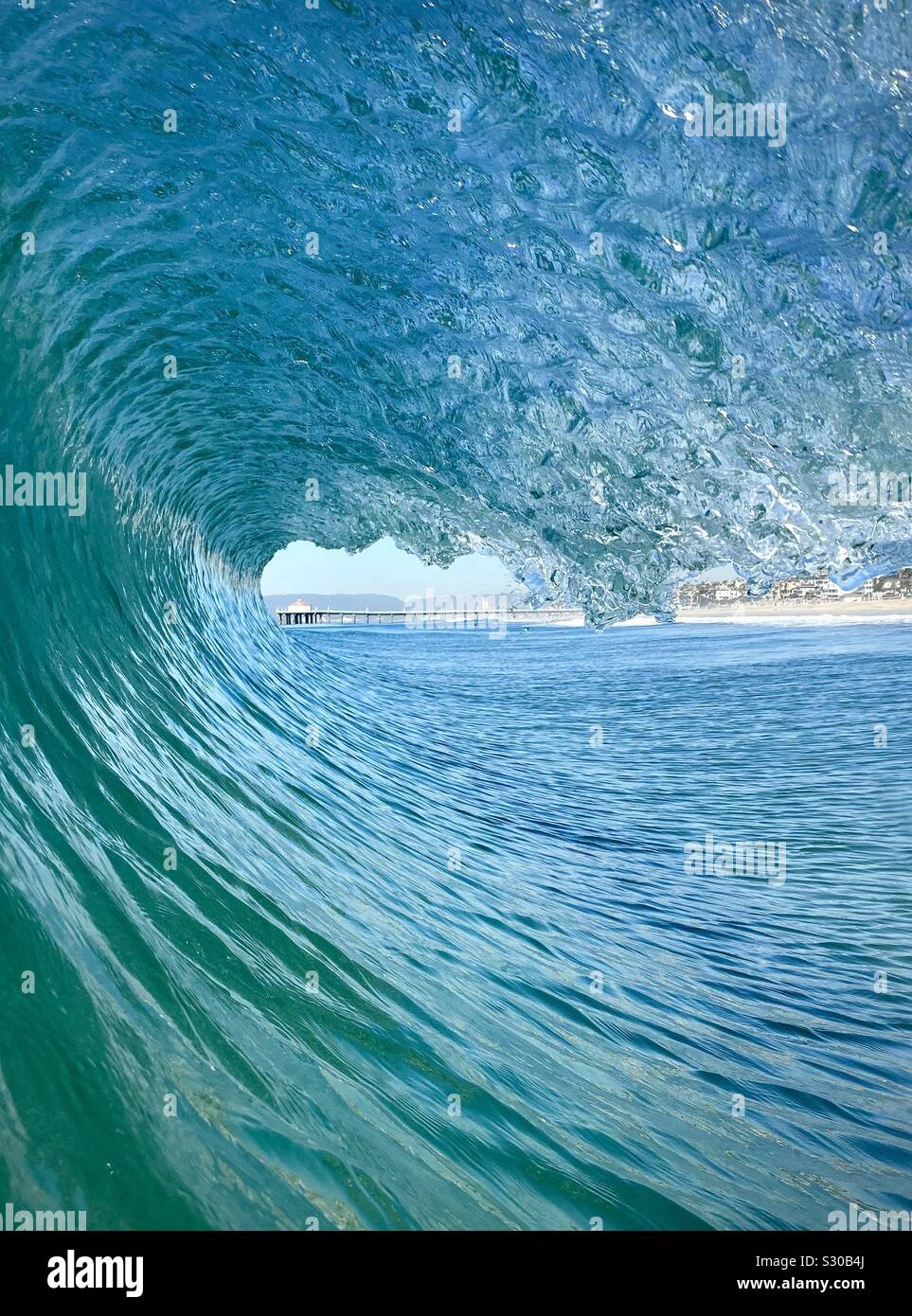 Innen aus einem fässerfüllen Wave mit Manhattan Beach Pier im Hintergrund. Manhattan Beach, Kalifornien, USA Stockfoto