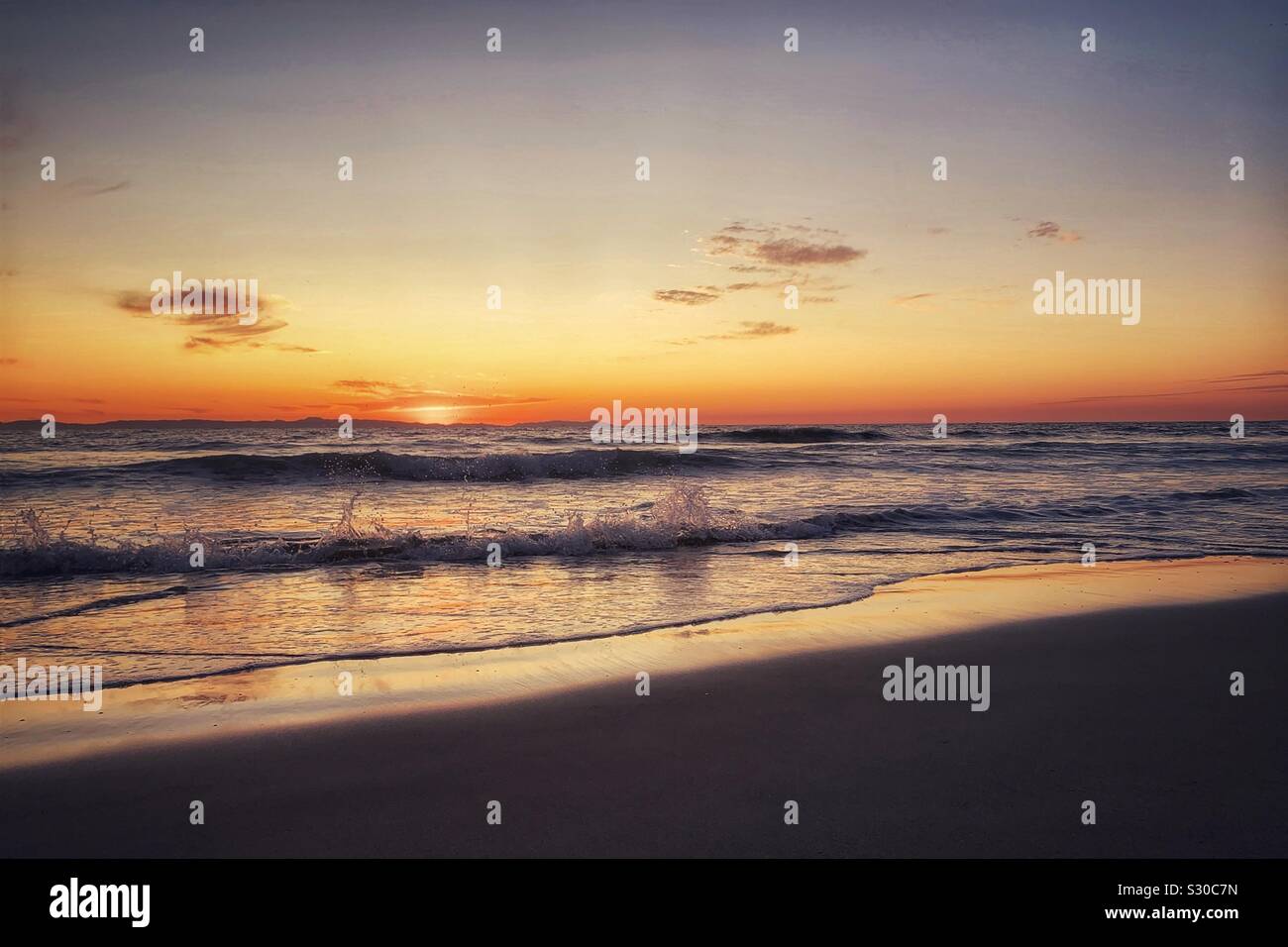 California Sunset mit Wellen, die auf sandigen Strand. Stockfoto