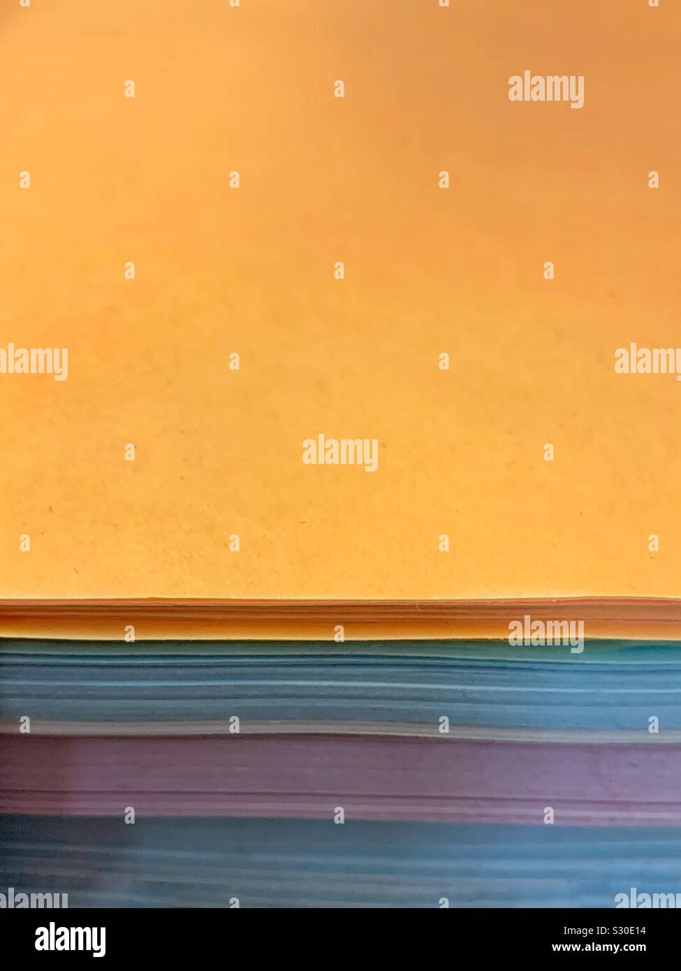 Stapel von Gelb Blau und Lila farbiges Papier Stockfoto