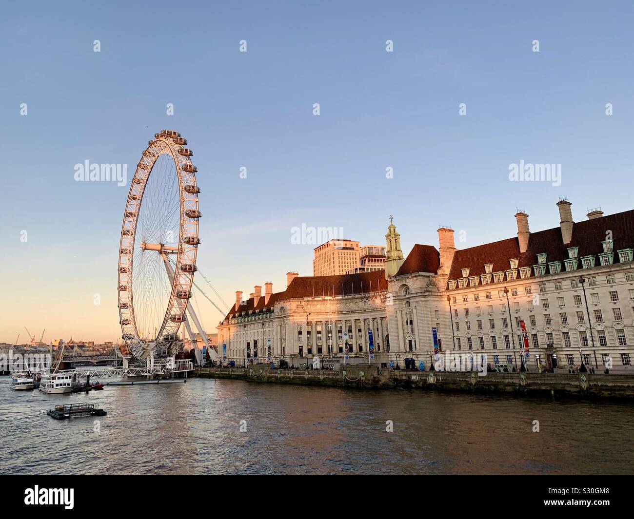 London, UK, 2. Dezember 2019: Millennium Wheel aka London Eye und der County Hall von Westminster Bridge gesehen. Am späten Montag Nachmittag. - Smartphone-aufgenommenes Stockfoto